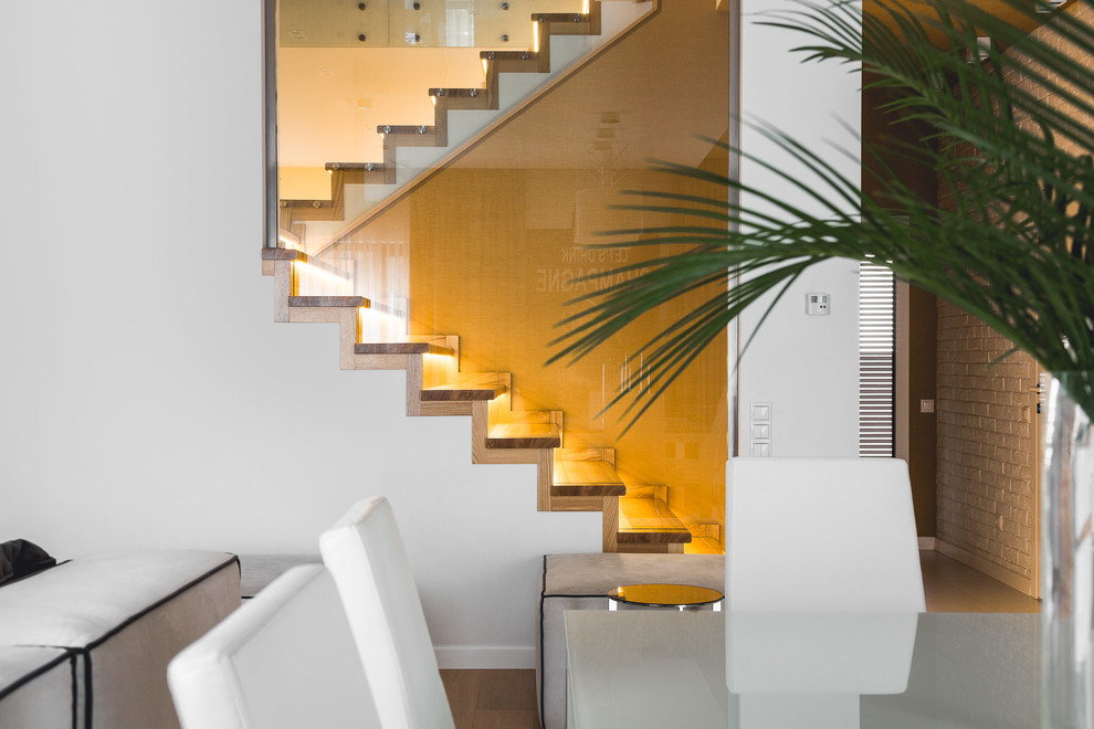 Diseño de escalera en U actual con escalones de madera, contrahuellas de madera y barandilla de vidrio