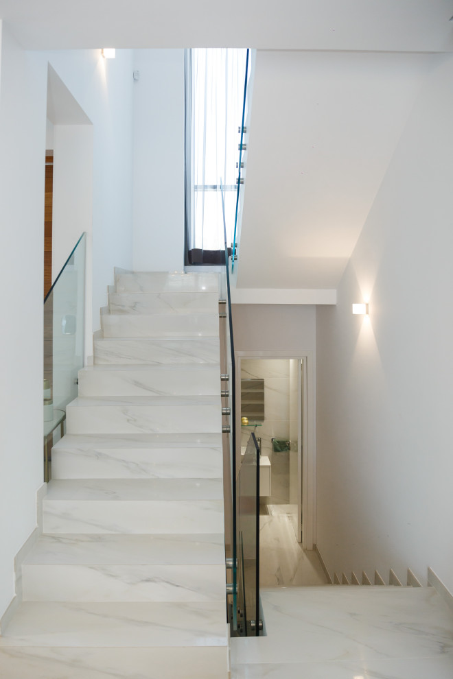 Modelo de escalera en U contemporánea de tamaño medio con escalones con baldosas, contrahuellas con baldosas y/o azulejos y barandilla de vidrio
