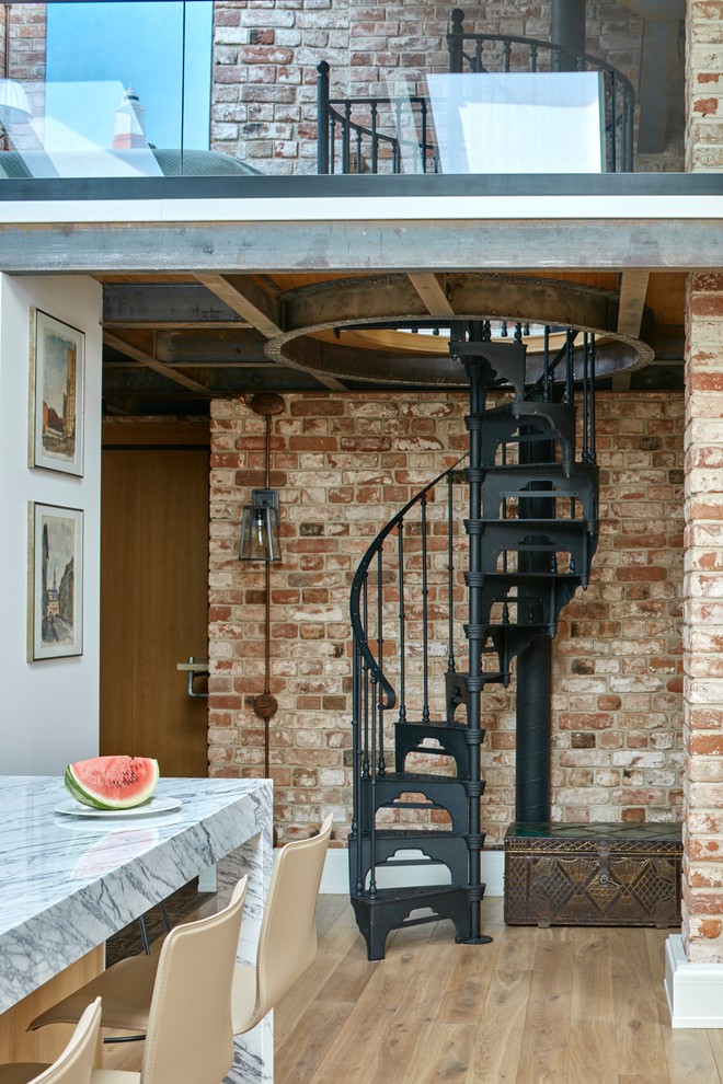 На фото: винтовая лестница в стиле лофт с металлическими ступенями и металлическими перилами без подступенок