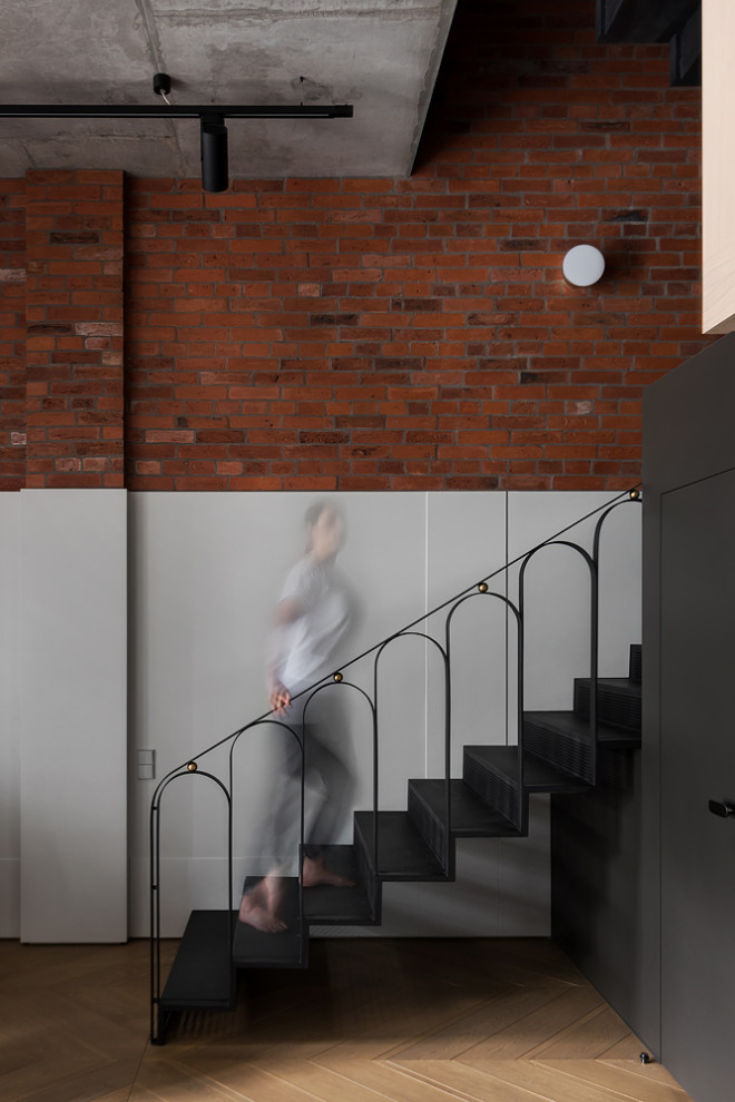 Ejemplo de escalera en L minimalista de tamaño medio con escalones de metal, contrahuellas de metal, barandilla de metal y panelado