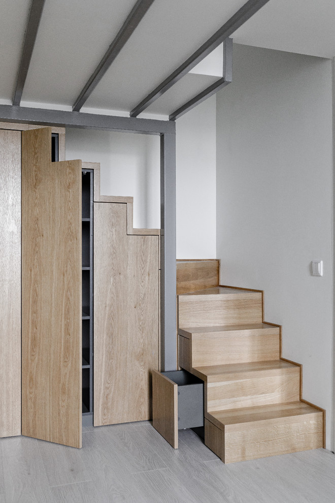На фото: угловая деревянная лестница в скандинавском стиле с деревянными ступенями и кладовкой или шкафом под ней