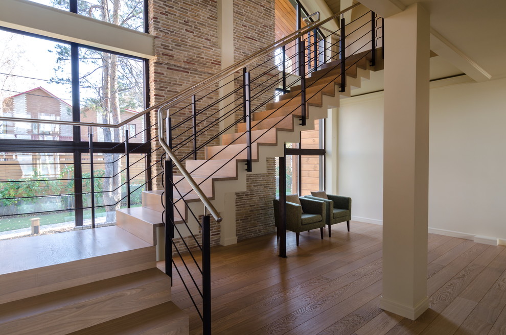 На фото: п-образная деревянная лестница в современном стиле с деревянными ступенями и металлическими перилами с