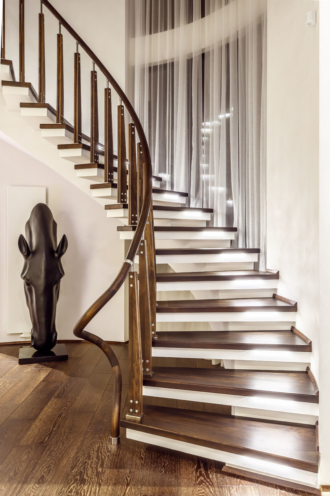 Cette image montre un escalier sans contremarche courbe design avec un garde-corps en matériaux mixtes.