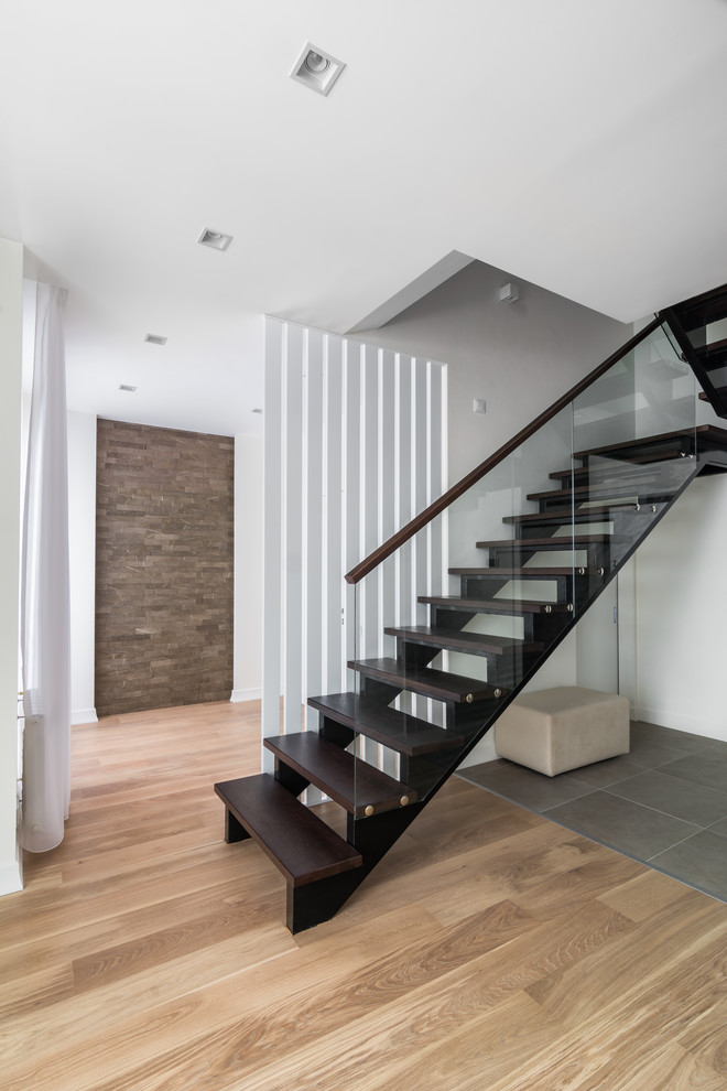 Пример оригинального дизайна: прямая лестница среднего размера в современном стиле с деревянными ступенями и стеклянными перилами без подступенок