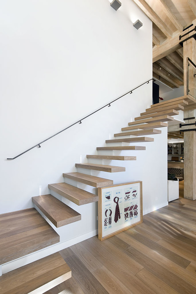 Imagen de escalera suspendida industrial sin contrahuella con escalones de madera y barandilla de metal