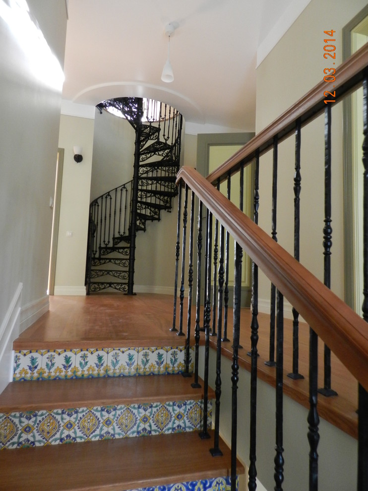 На фото: винтовая лестница среднего размера с металлическими ступенями, подступенками из плитки и металлическими перилами