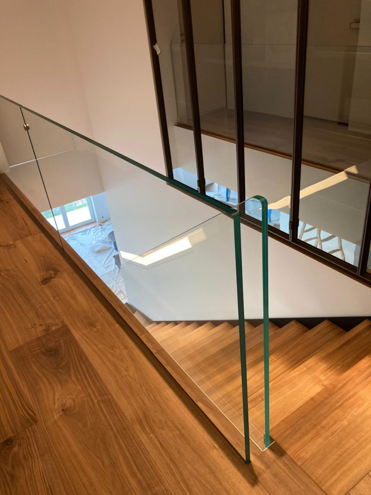 Свежая идея для дизайна: прямая лестница среднего размера в современном стиле с деревянными ступенями и стеклянными перилами - отличное фото интерьера