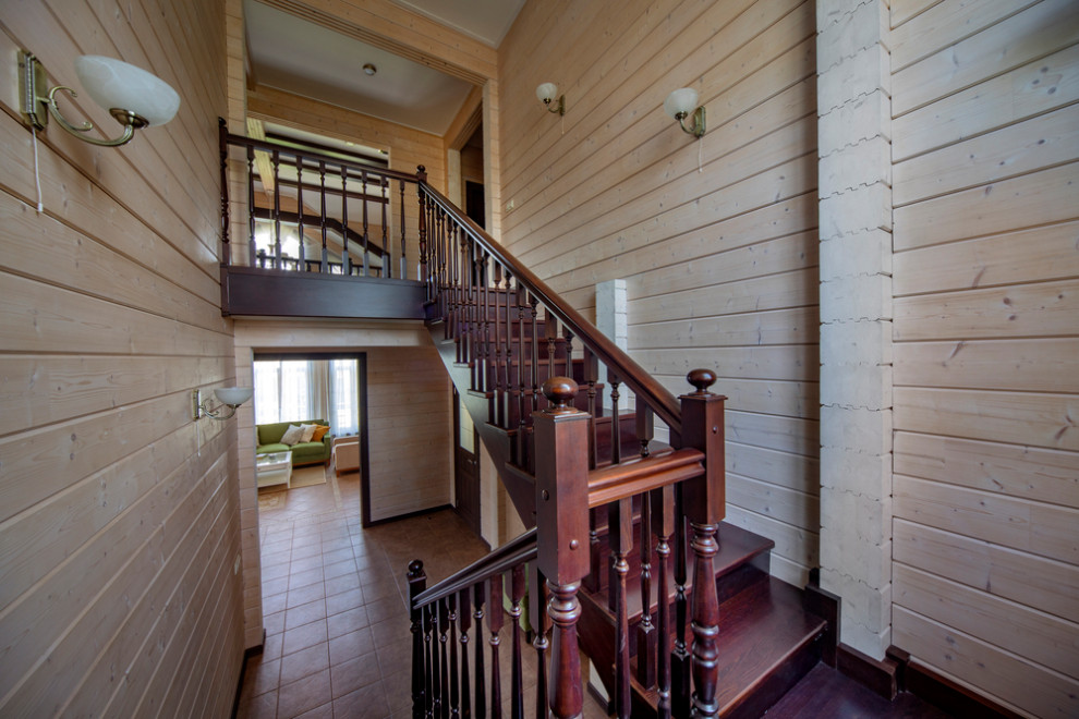 На фото: большая п-образная деревянная лестница в стиле рустика с деревянными ступенями, деревянными перилами и деревянными стенами