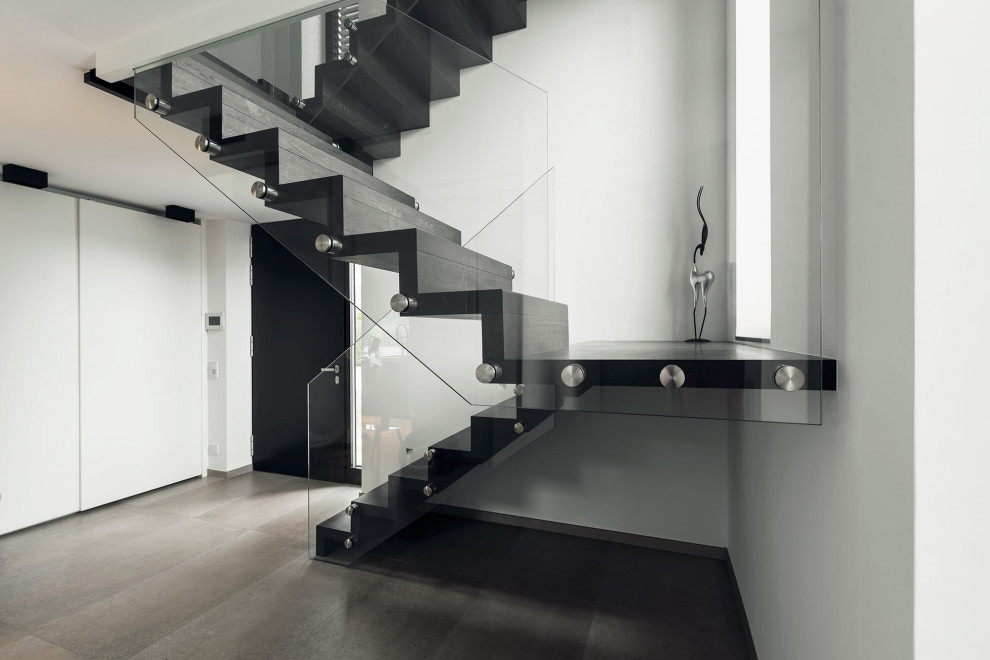 На фото: лестница в современном стиле с стеклянными перилами