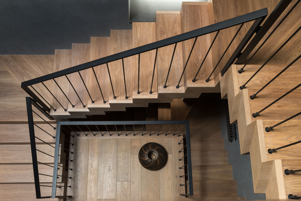 Diseño de escalera en U urbana de tamaño medio con escalones de madera, contrahuellas de madera y barandilla de metal