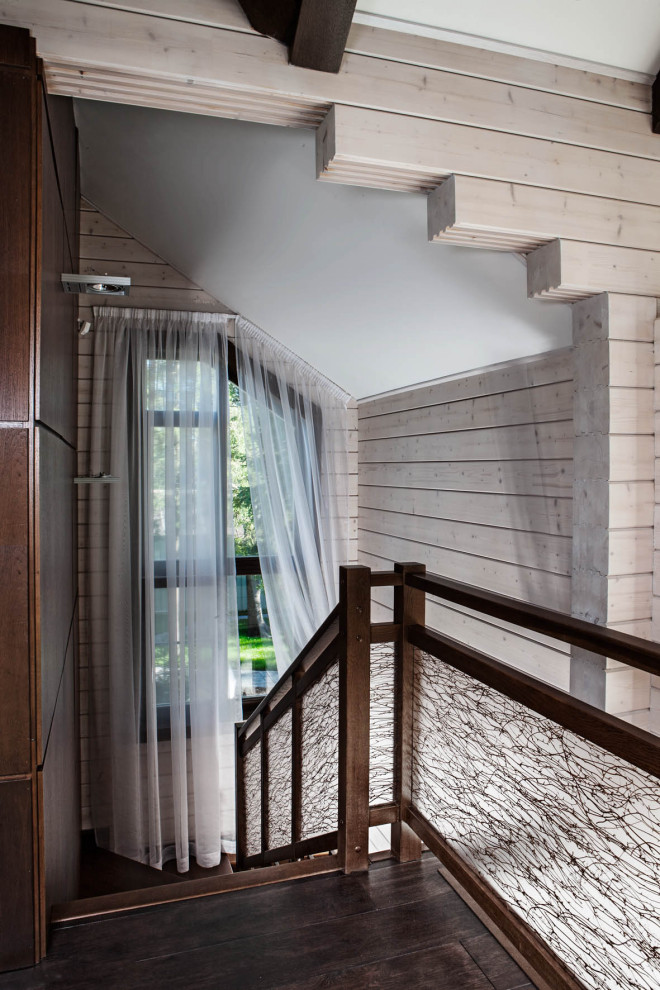 Cette photo montre un grand escalier tendance en U avec des marches en bois, des contremarches en bois, un garde-corps en verre et boiseries.