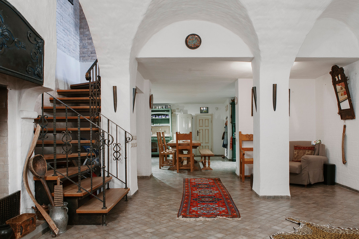 На фото: изогнутая лестница в средиземноморском стиле с деревянными ступенями и металлическими перилами без подступенок с