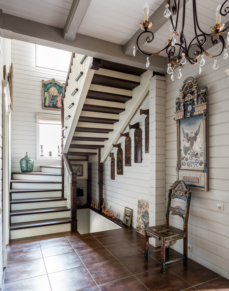 Diseño de escalera en U de estilo de casa de campo con escalones de madera, contrahuellas de madera y barandilla de madera