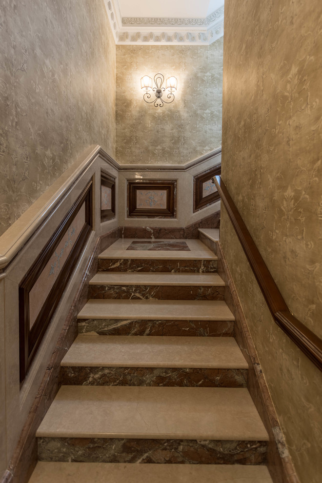 Cette image montre un grand escalier courbe en marbre avec des contremarches en marbre.
