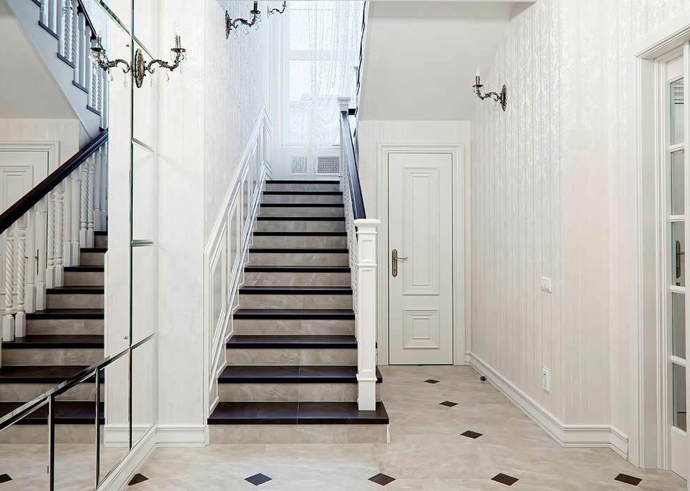 Ejemplo de escalera en U clásica de tamaño medio con escalones con baldosas, contrahuellas con baldosas y/o azulejos y barandilla de madera