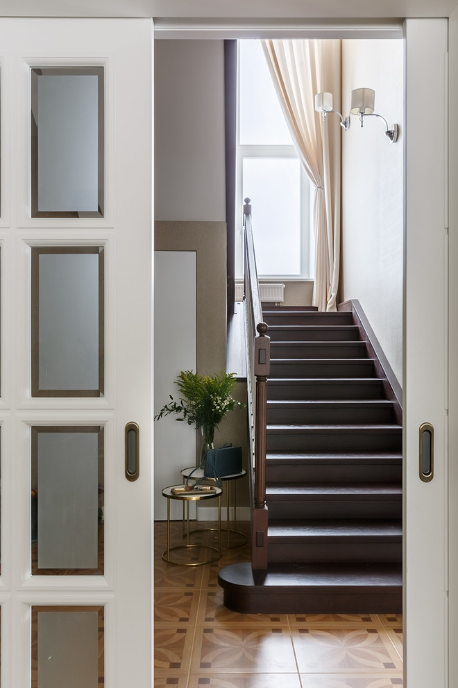 На фото: п-образная деревянная лестница среднего размера в стиле неоклассика (современная классика) с деревянными ступенями и деревянными перилами с