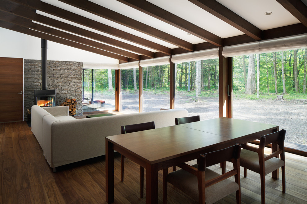 Imagen de salón abierto escandinavo con estufa de leña, suelo de madera en tonos medios, marco de chimenea de piedra y suelo marrón