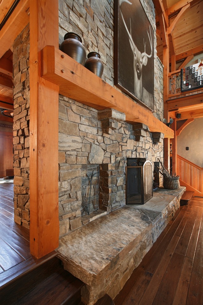 Inspiration for a large rustic mezzanine living room in Other with beige walls, dark hardwood flooring, a standard fireplace and a stone fireplace surround.