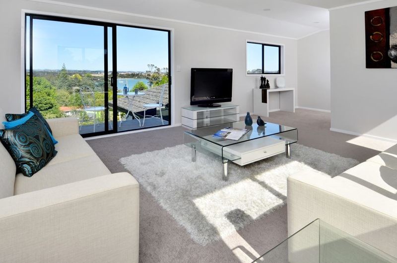 Small beach style open plan living room in Auckland with white walls, carpet and a freestanding tv.
