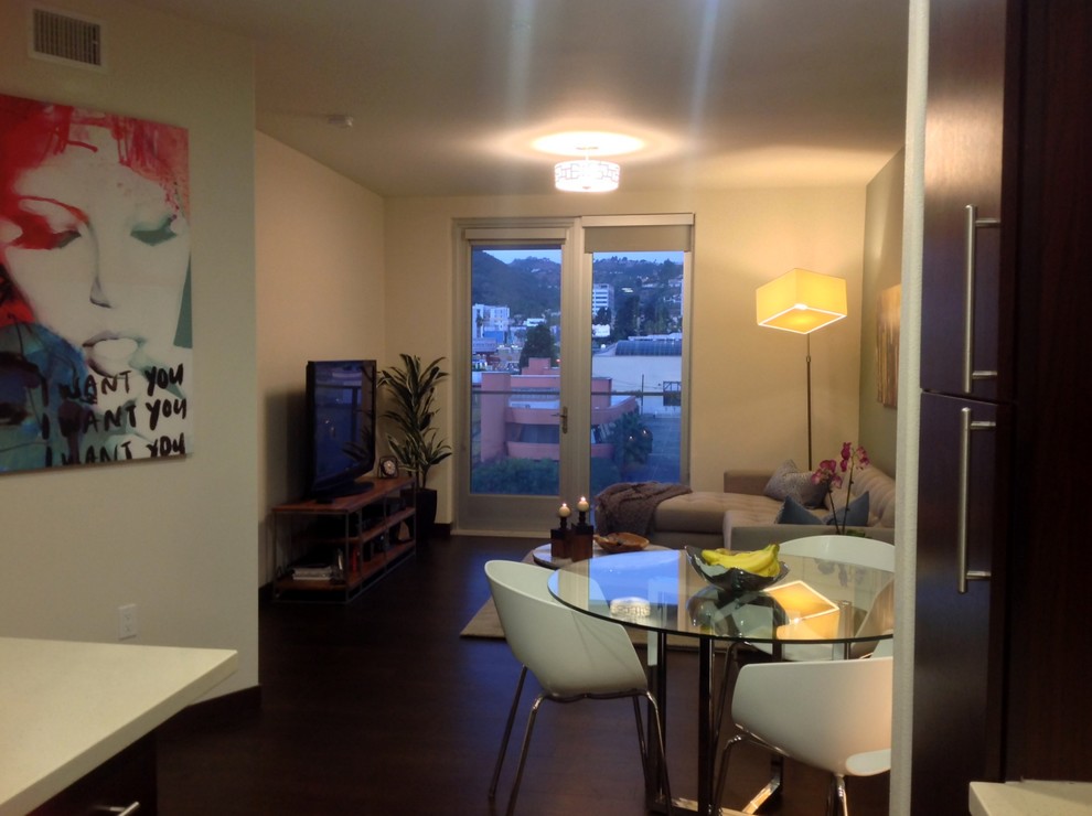 Kleines, Offenes Modernes Wohnzimmer ohne Kamin mit blauer Wandfarbe, dunklem Holzboden, braunem Boden und freistehendem TV in Los Angeles