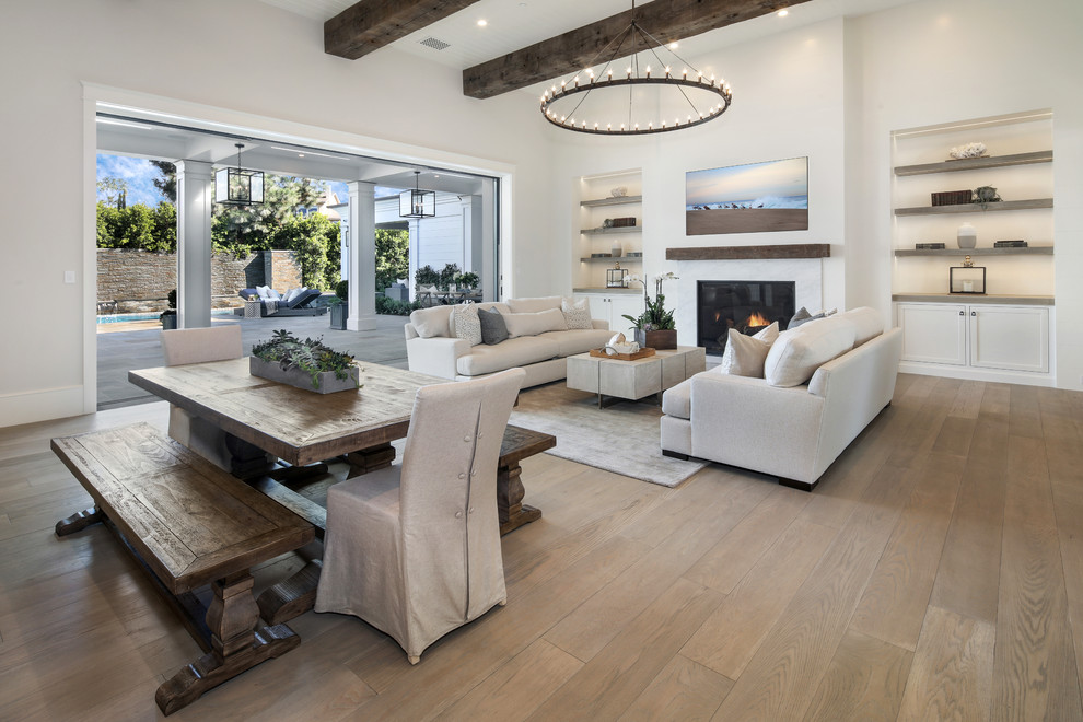 Offenes Klassisches Wohnzimmer mit weißer Wandfarbe, braunem Holzboden, Kamin und braunem Boden in Orange County