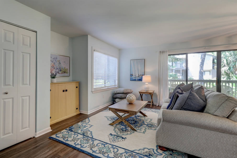 На фото: открытая гостиная комната среднего размера в морском стиле с синими стенами, полом из винила, отдельно стоящим телевизором и коричневым полом