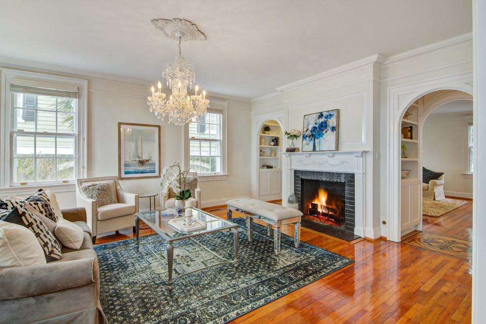 Inspiration for a large timeless enclosed medium tone wood floor and brown floor living room remodel in Charleston with a standard fireplace and a brick fireplace