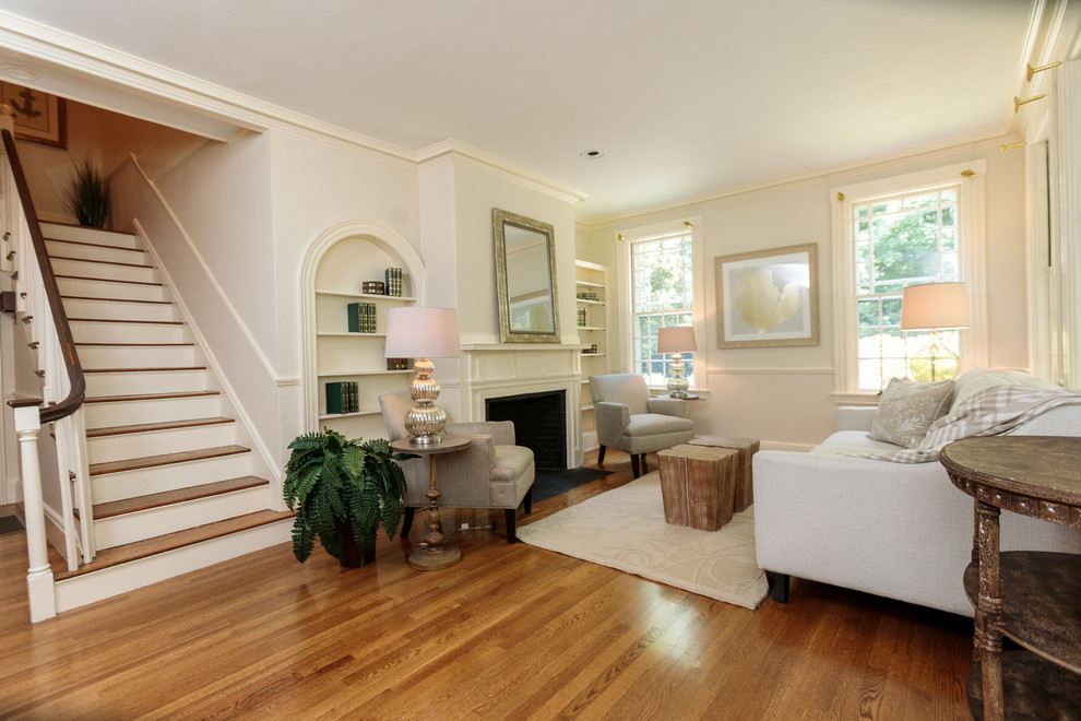 Exemple d'un grand salon chic ouvert avec une bibliothèque ou un coin lecture, un mur beige, un sol en bois brun, une cheminée standard et un manteau de cheminée en bois.