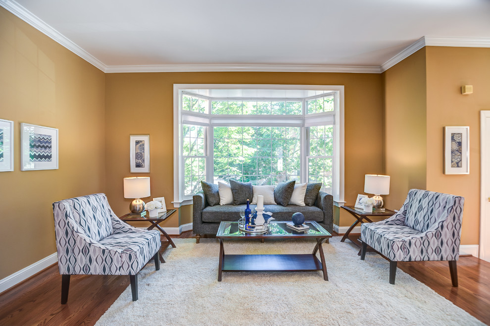 Foto di un soggiorno classico aperto con sala formale, pareti gialle, pavimento in legno massello medio, nessun camino e nessuna TV