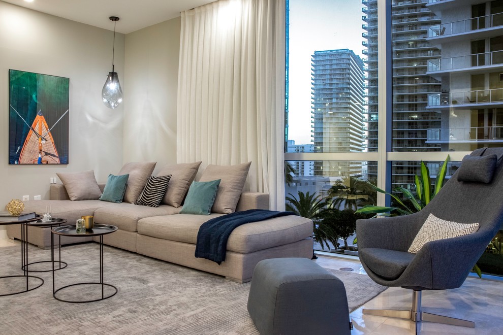 Example of a small trendy open concept limestone floor and beige floor living room design in Miami with gray walls and a media wall
