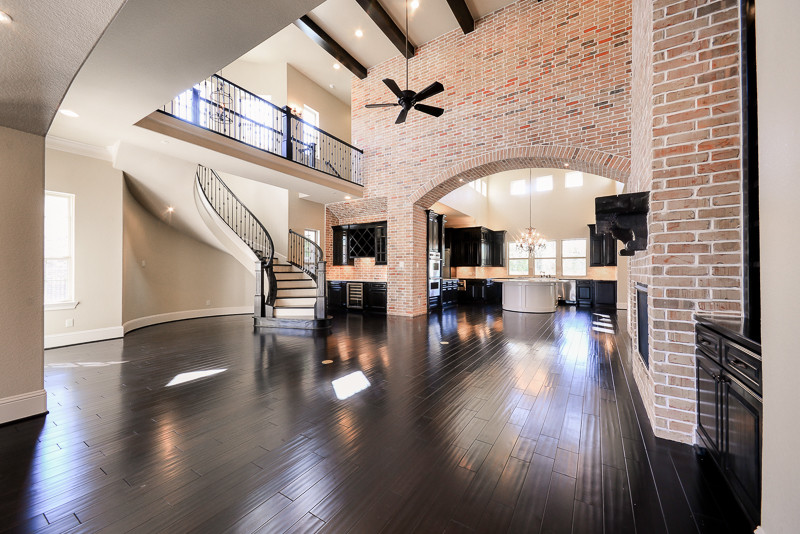 Inspiration for a large transitional open concept dark wood floor living room remodel in Houston with a bar, beige walls, a standard fireplace and a brick fireplace