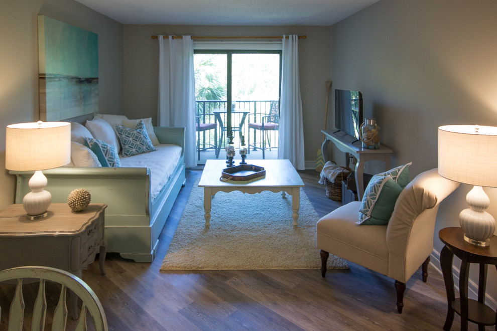 Immagine di un piccolo soggiorno stile marino aperto con pareti beige, pavimento in vinile, TV autoportante e pavimento marrone