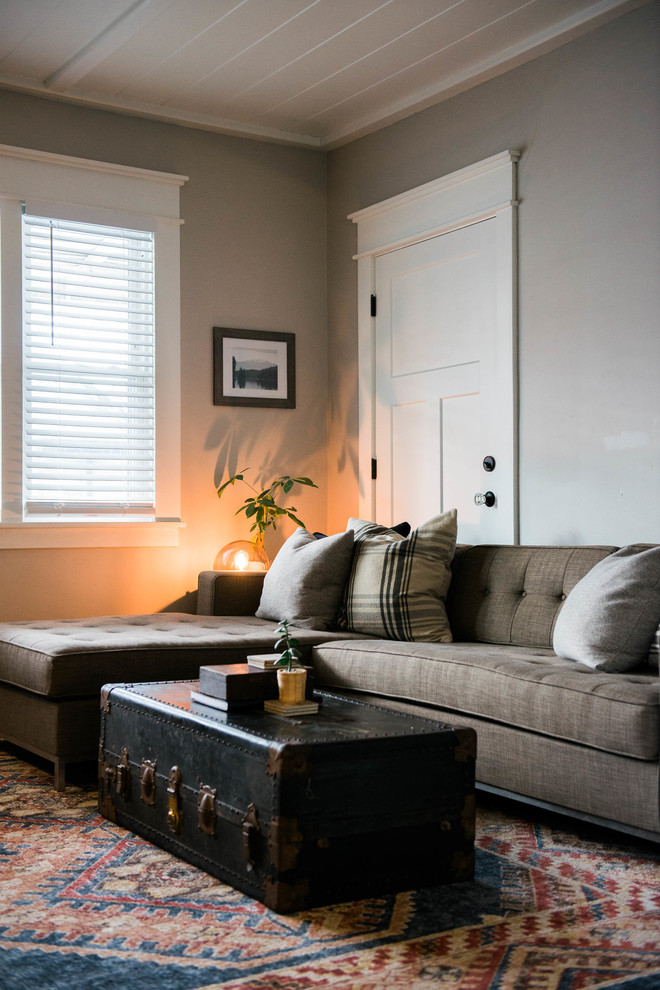 Bild på ett litet eklektiskt vardagsrum, med grå väggar, mörkt trägolv, en standard öppen spis, en spiselkrans i tegelsten och en väggmonterad TV