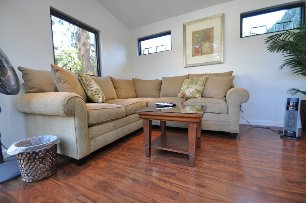 Foto di un piccolo soggiorno design chiuso con libreria, pareti bianche, pavimento in laminato e TV autoportante