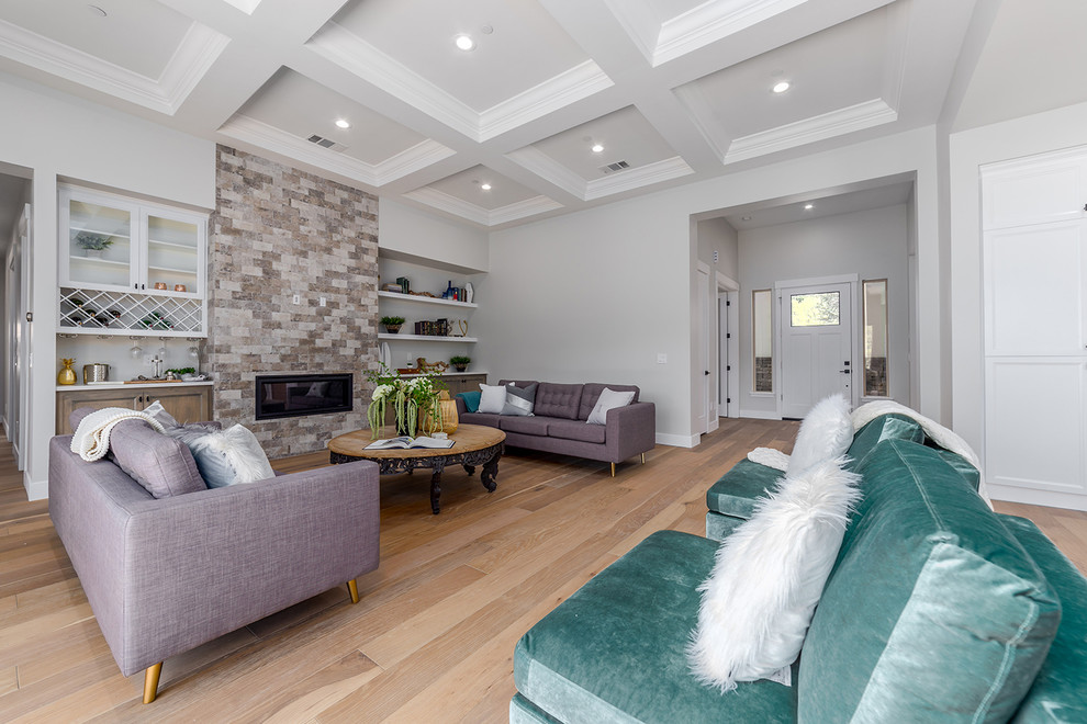 Large cottage open concept light wood floor and beige floor living room photo in Sacramento with gray walls, a standard fireplace, a stone fireplace and a media wall