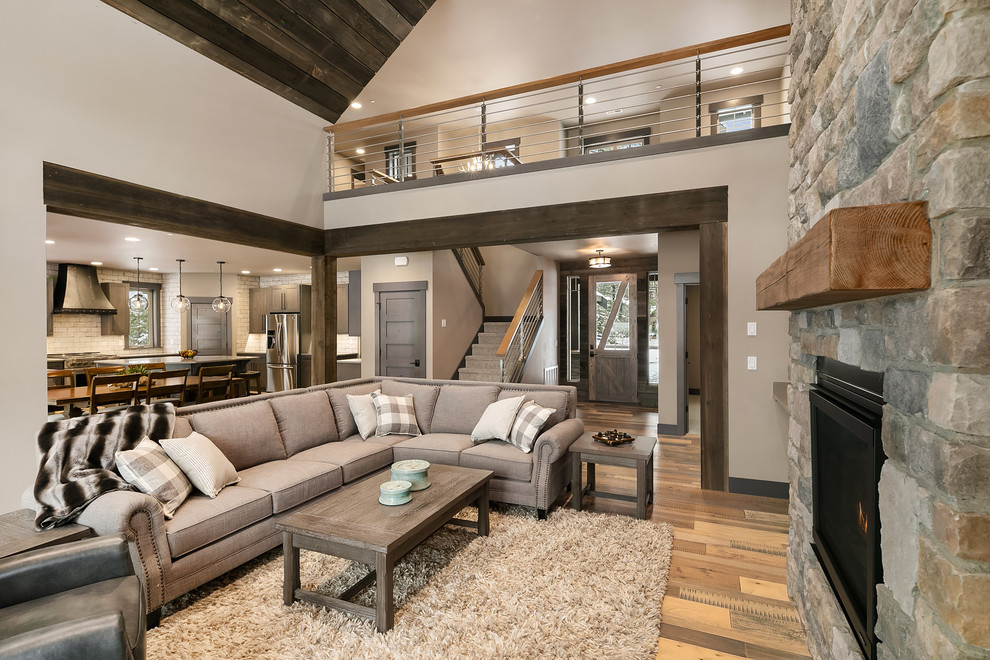 Inspiration for a rustic living room in Seattle with white walls, medium hardwood flooring, a standard fireplace, a stone fireplace surround and brown floors.