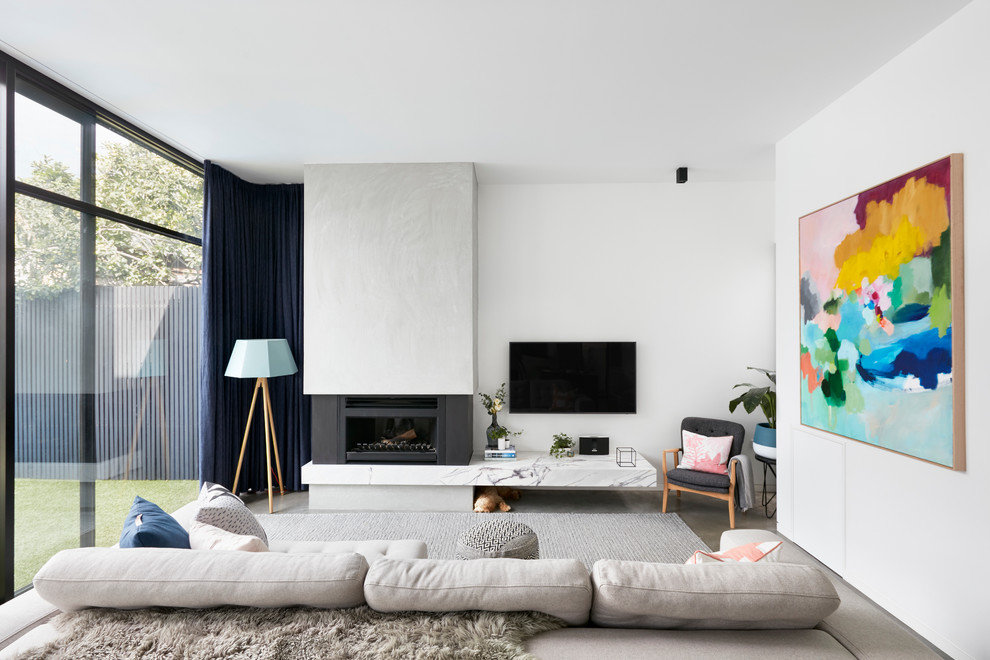 Идея дизайна: изолированная гостиная комната в современном стиле с белыми стенами, бетонным полом, стандартным камином, фасадом камина из бетона и телевизором на стене