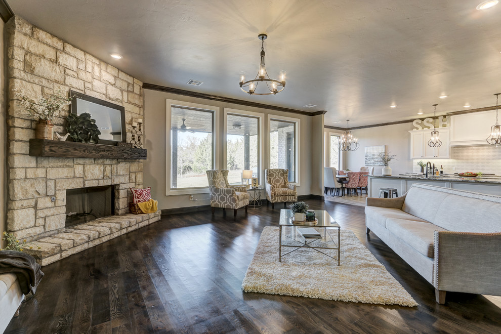Großes, Offenes Klassisches Wohnzimmer mit beiger Wandfarbe, braunem Holzboden, Kamin, Kaminumrandung aus Stein und braunem Boden in Oklahoma City