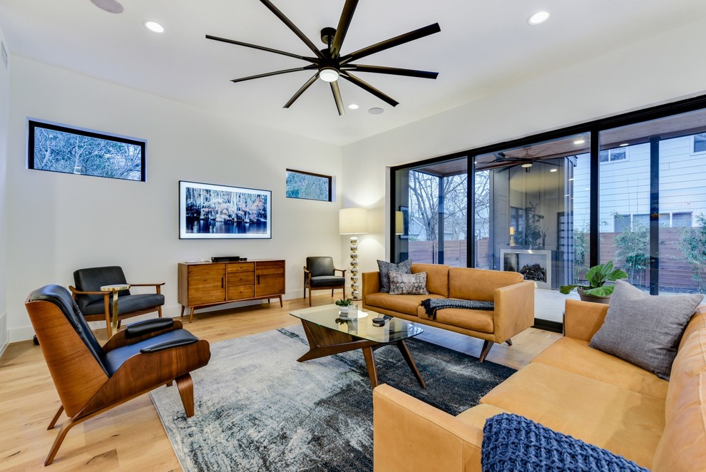 Immagine di un soggiorno moderno con pareti bianche, parquet chiaro, TV a parete e pavimento beige