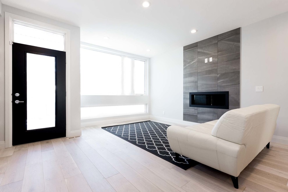 Mittelgroßes, Repräsentatives, Offenes Modernes Wohnzimmer mit weißer Wandfarbe, hellem Holzboden, Gaskamin und gefliester Kaminumrandung in Edmonton