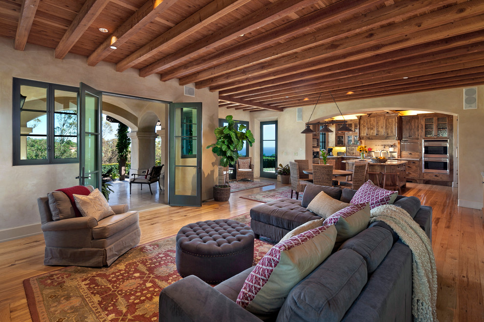 Esempio di un soggiorno mediterraneo aperto con pareti beige e pavimento in legno massello medio