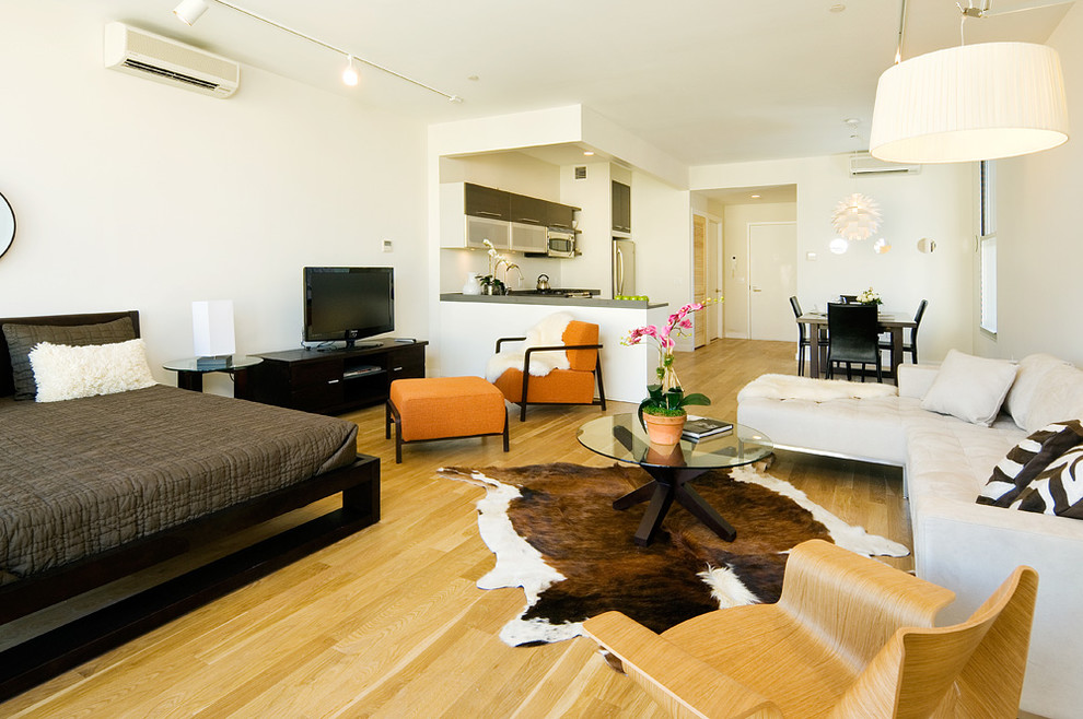 This is an example of a medium sized contemporary mezzanine living room in New York with white walls, light hardwood flooring, a freestanding tv and no fireplace.