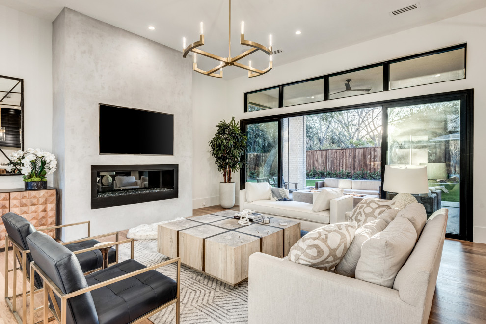Inspiration for a large transitional open concept light wood floor and brown floor living room remodel in Dallas with white walls, a standard fireplace, a plaster fireplace and a wall-mounted tv
