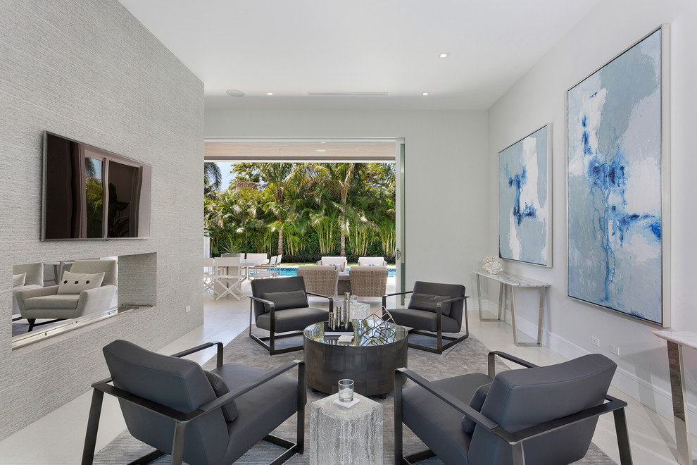 Offenes, Mittelgroßes Modernes Wohnzimmer mit grauer Wandfarbe, Tunnelkamin, gefliester Kaminumrandung, TV-Wand und grauem Boden in Miami