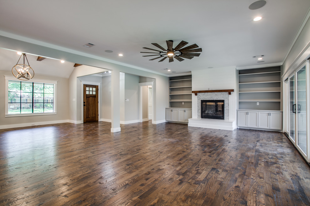 Großes, Offenes Klassisches Wohnzimmer mit grauer Wandfarbe, braunem Holzboden, Kamin, gefliester Kaminumrandung, TV-Wand und braunem Boden in Dallas