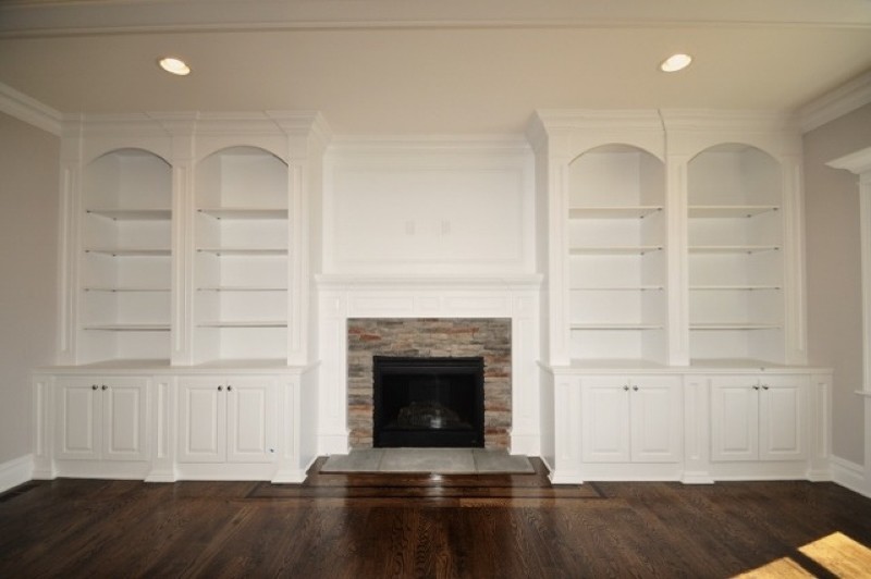Cette image montre un salon minimaliste ouvert avec un mur gris, parquet foncé, une cheminée standard et un manteau de cheminée en pierre.
