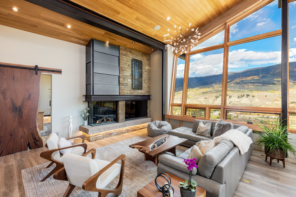 Inspiration for a rustic medium tone wood floor and brown floor living room remodel in Denver with white walls, a standard fireplace and a stone fireplace