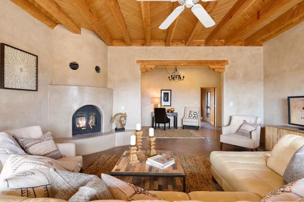 Southwest enclosed brown floor, exposed beam and wood ceiling living room photo in Albuquerque with beige walls and a corner fireplace