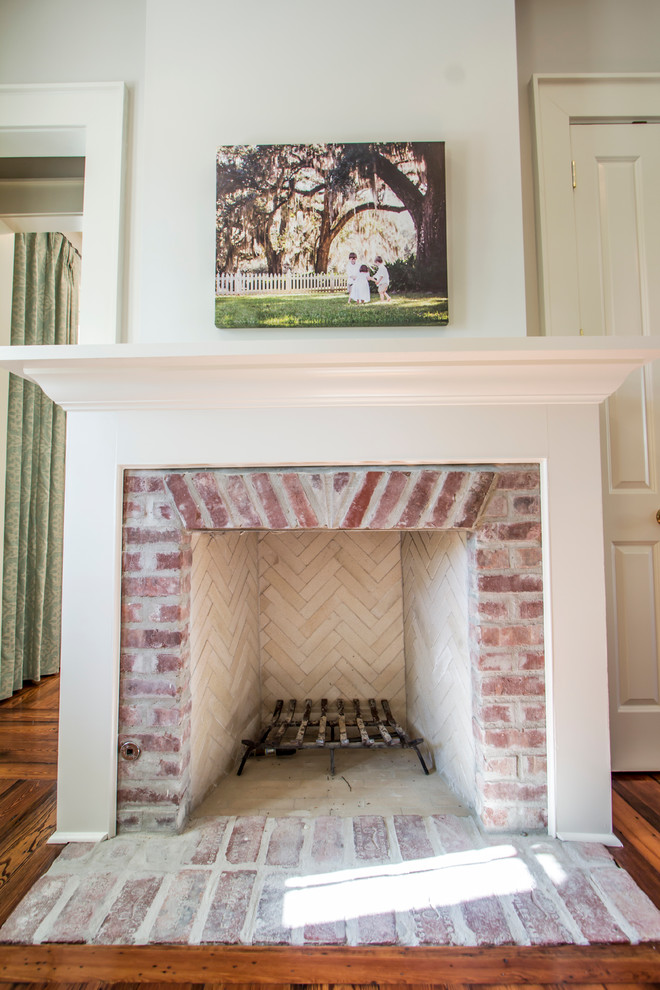 Large elegant formal and enclosed medium tone wood floor living room photo in New Orleans with white walls, a standard fireplace, a brick fireplace and no tv