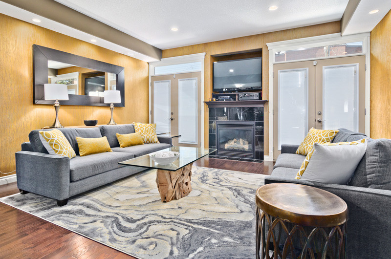 Стильный дизайн: изолированная гостиная комната среднего размера в современном стиле с желтыми стенами, паркетным полом среднего тона, стандартным камином, фасадом камина из камня и отдельно стоящим телевизором - последний тренд